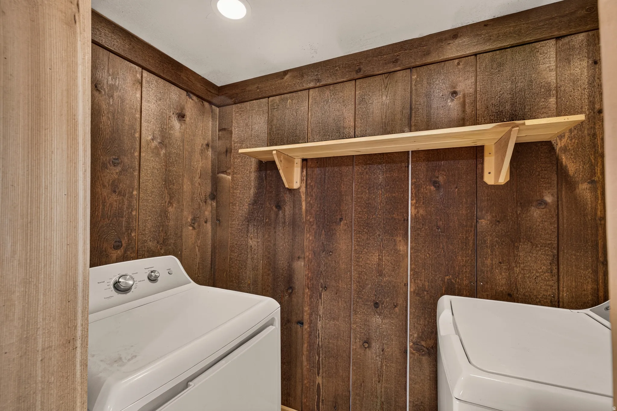 Utility area featuring vertical wood paneling and a built-in wood shelf