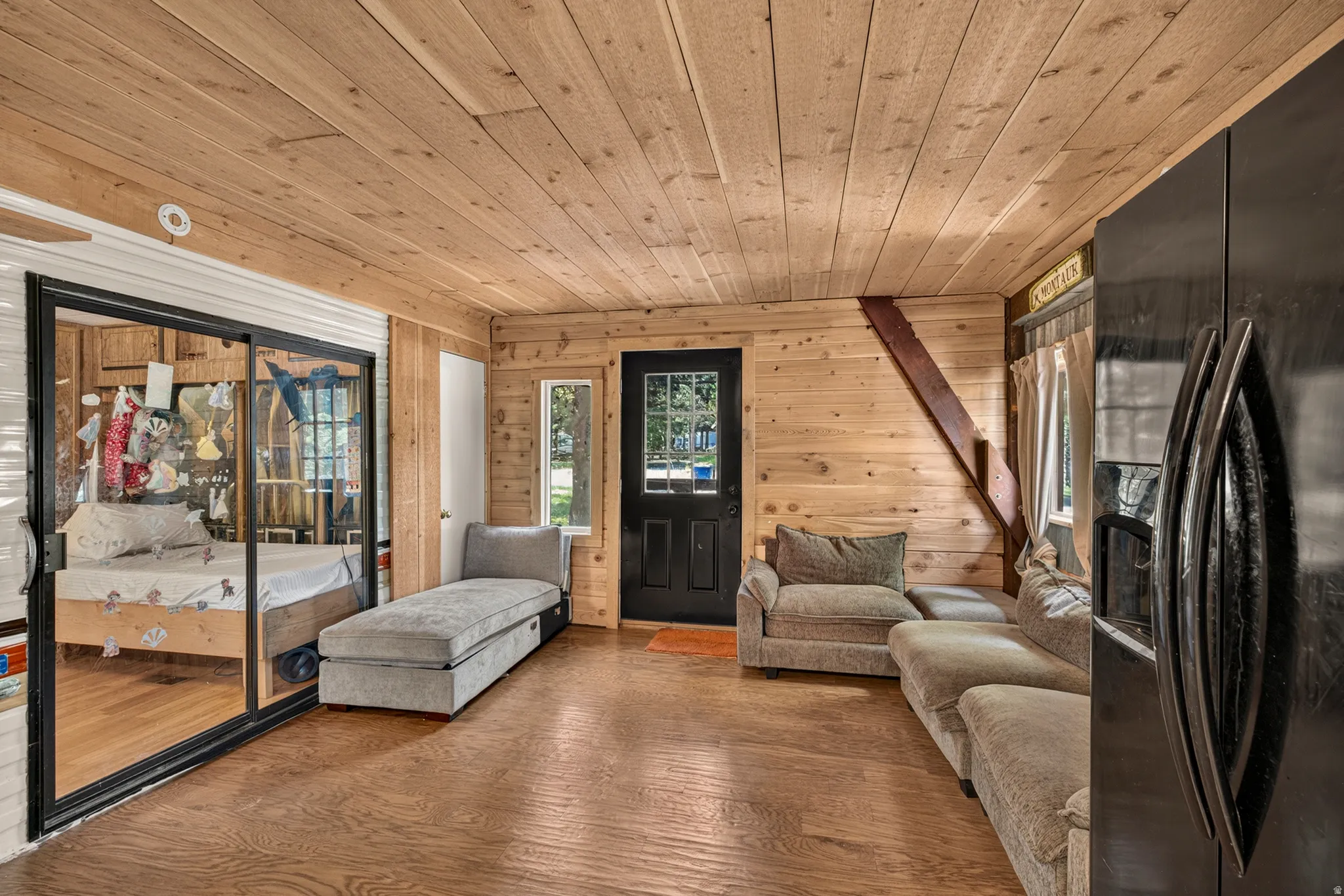 Living area featuring wood-finish flooring, natural wood plank walls, and a matching wood plank ceiling
