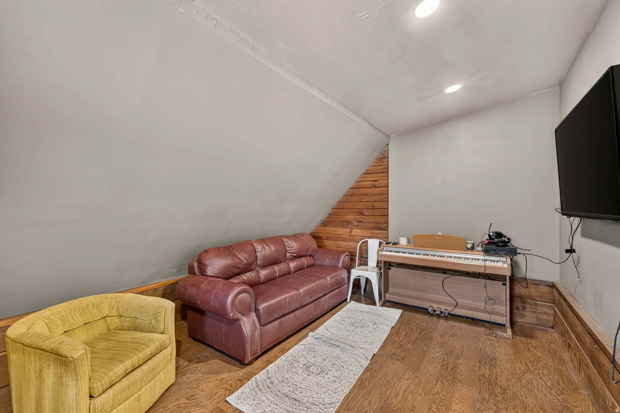 Attic space featuring wood-finish flooring, recessed lighting, and sloped walls