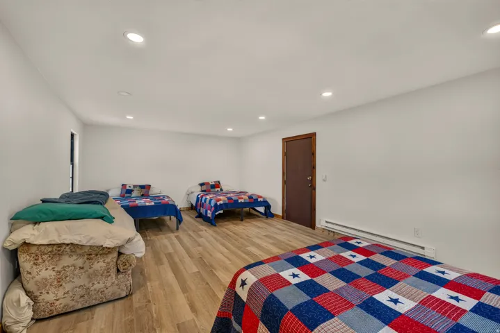 Spacious room featuring wood-finish flooring, recessed lighting, and white painted walls