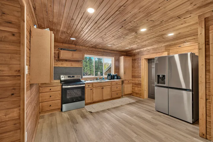 Kitchen with wood-paneled walls and ceiling, recessed lighting, and wood-finish flooring