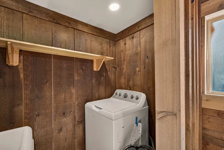Vertical wood paneling with a light wood shelf and a single ceiling light fixture