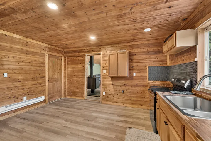 Open concept kitchen with wood-finish flooring, wood-paneled walls, and matching wood-finish cabinetry