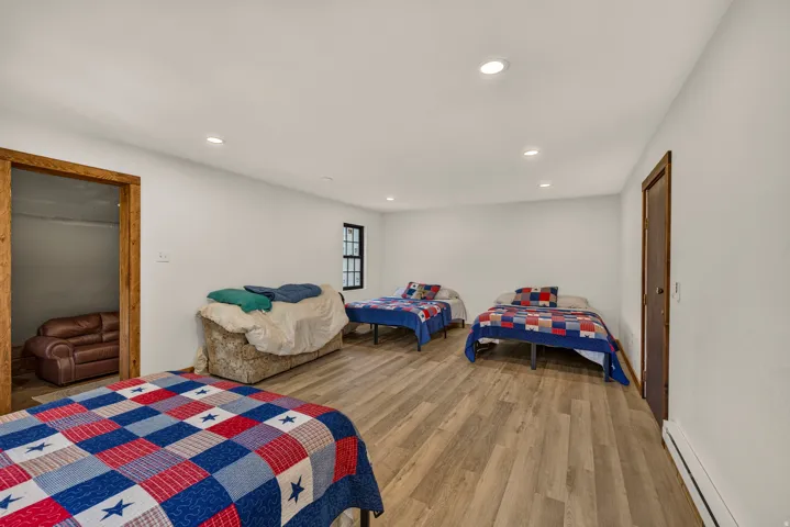 Spacious room featuring wood-finish flooring, recessed lighting, white walls, and a black-framed window