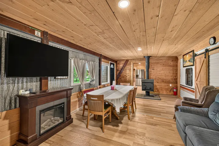 Living area featuring a wood-plank ceiling, wood-finish flooring, and a wood-burning stove