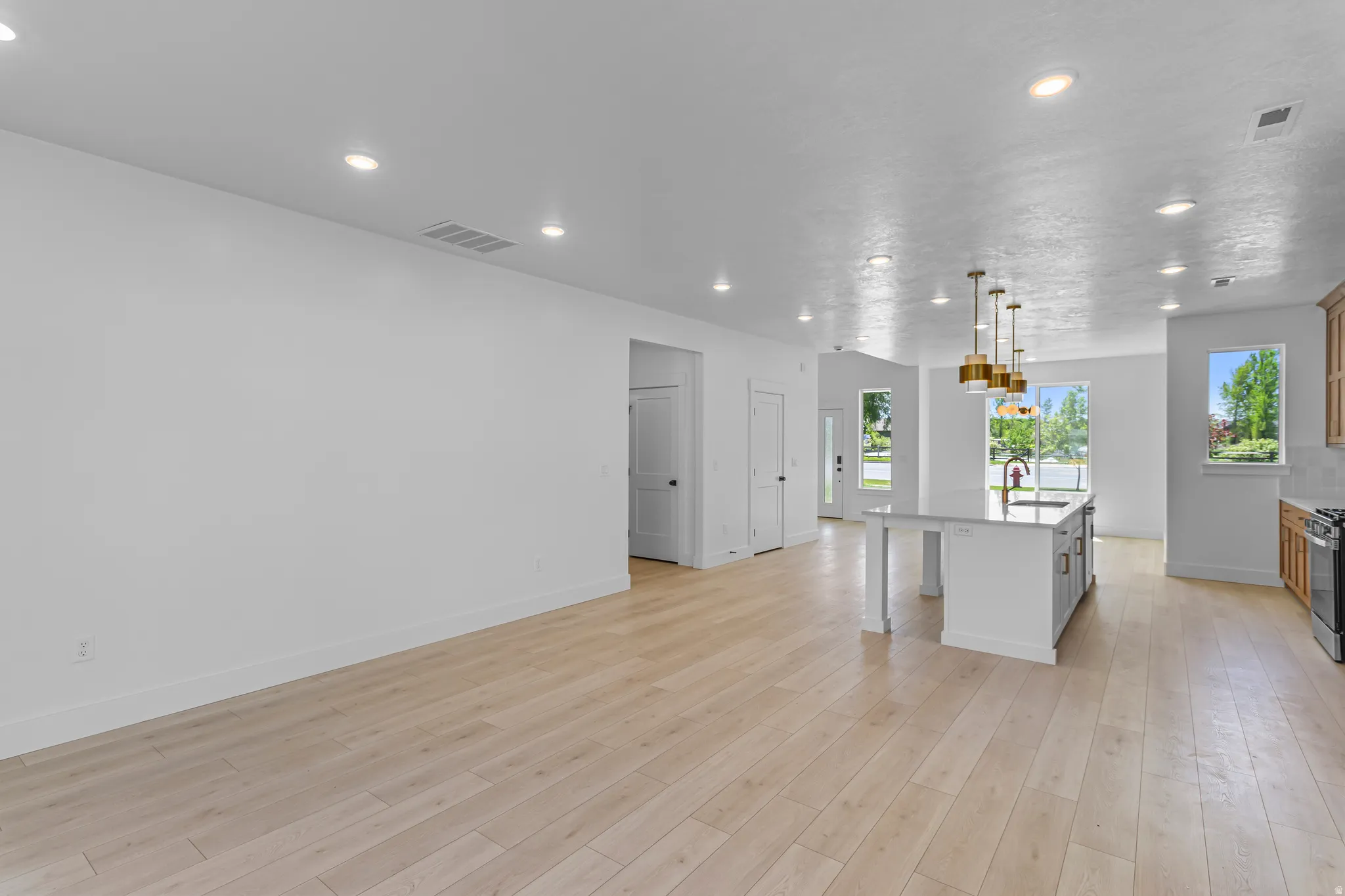 Open-concept living area featuring light wood-finish flooring, recessed lighting, and white wall finishes
