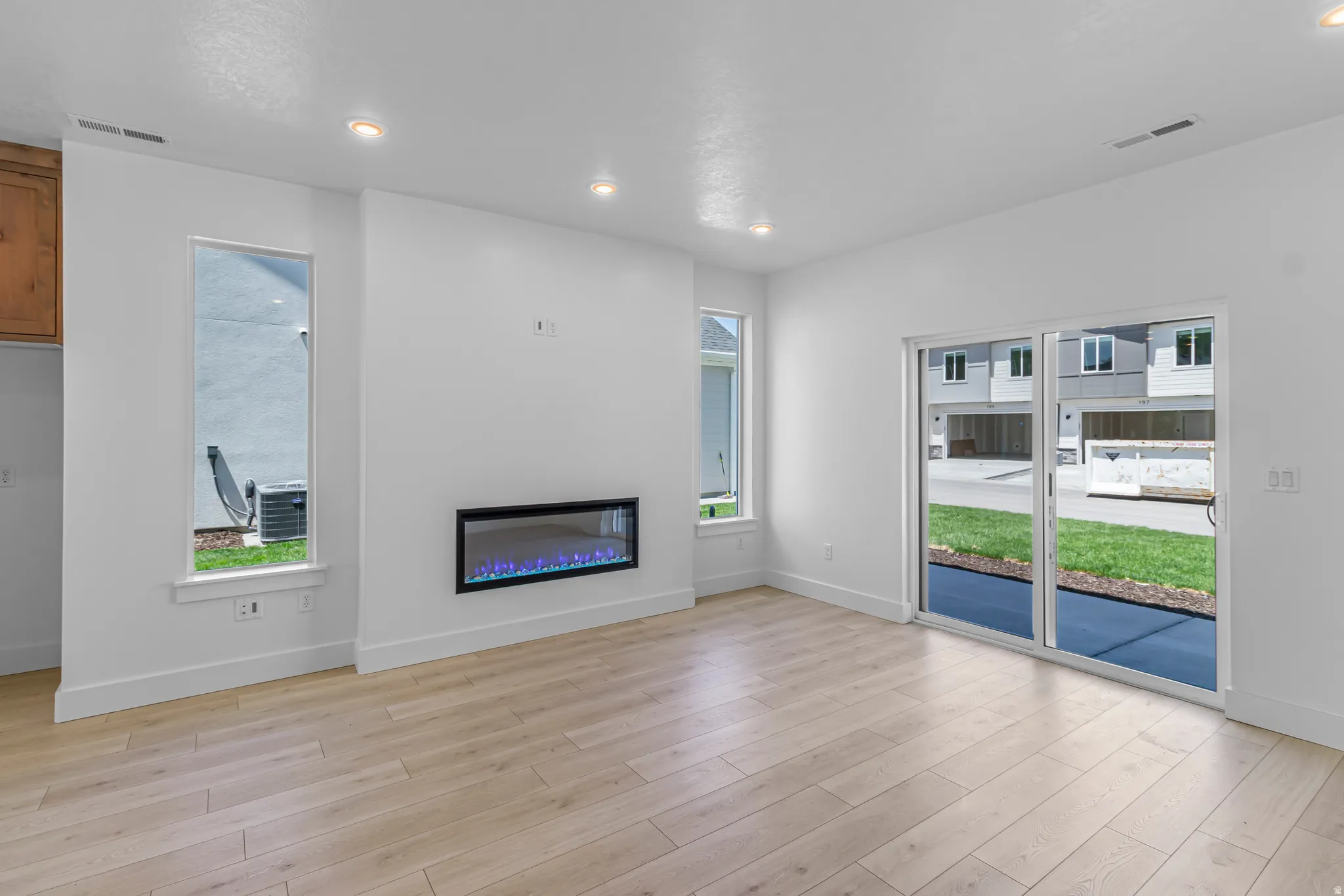 Bright interior with wood-finish flooring, featuring a built-in electric fireplace and recessed lighting