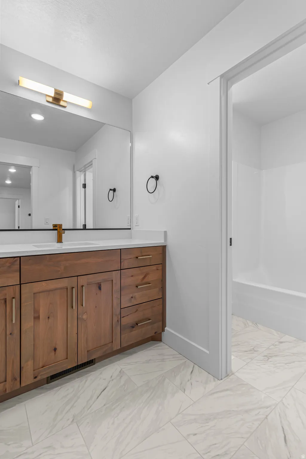 Double vanity featuring wood cabinetry, white countertops, and dual sinks with gold-toned fixtures