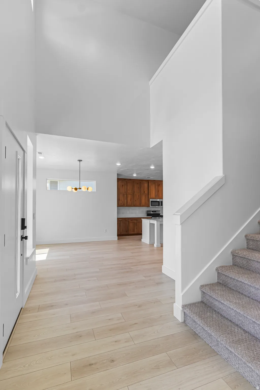 Soaring vaulted ceiling entryway featuring light wood-finish flooring