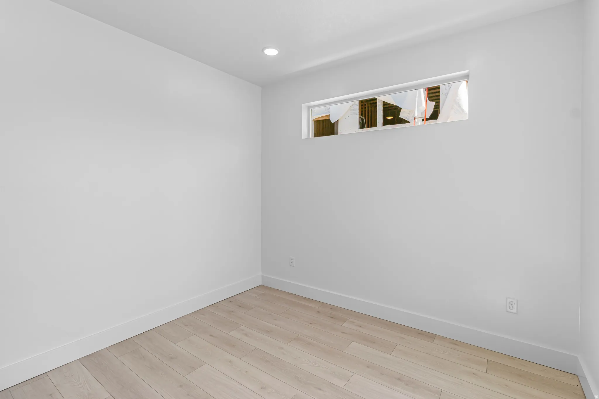 Room featuring light wood-finish flooring, white painted walls, and a horizontal window