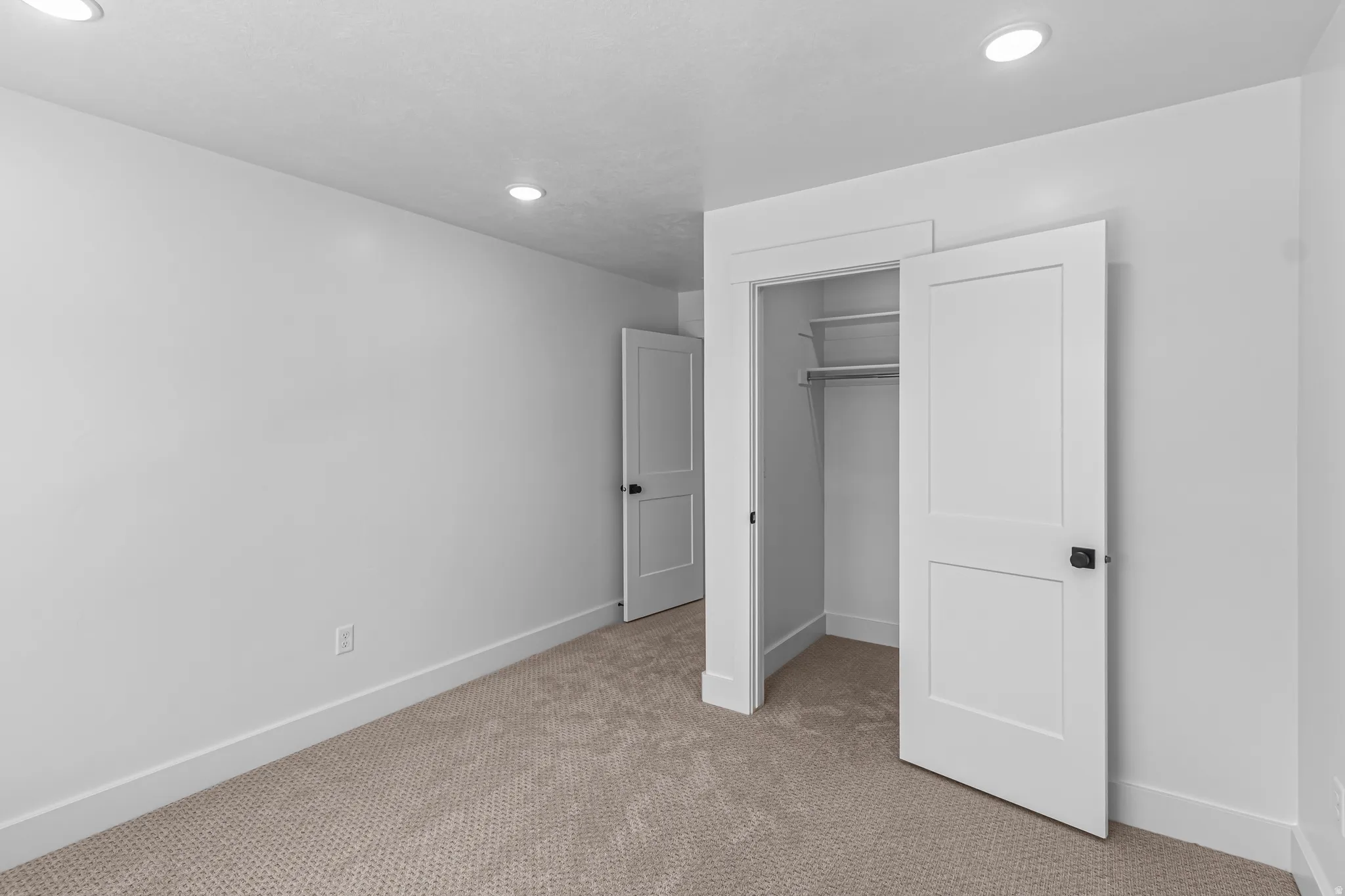 Carpeted room featuring recessed lighting, a closet with shelving and hanging rod, and two panel doors with matte black hardware
