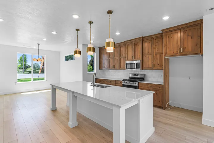 Modern kitchen featuring a large center island with a white countertop, wood-finish cabinetry, stainless steel appliances, a tile backsplash, and recessed lighting