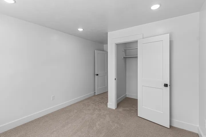 Carpeted room featuring recessed lighting, a closet with shelving and hanging rod, and two panel doors with matte black hardware