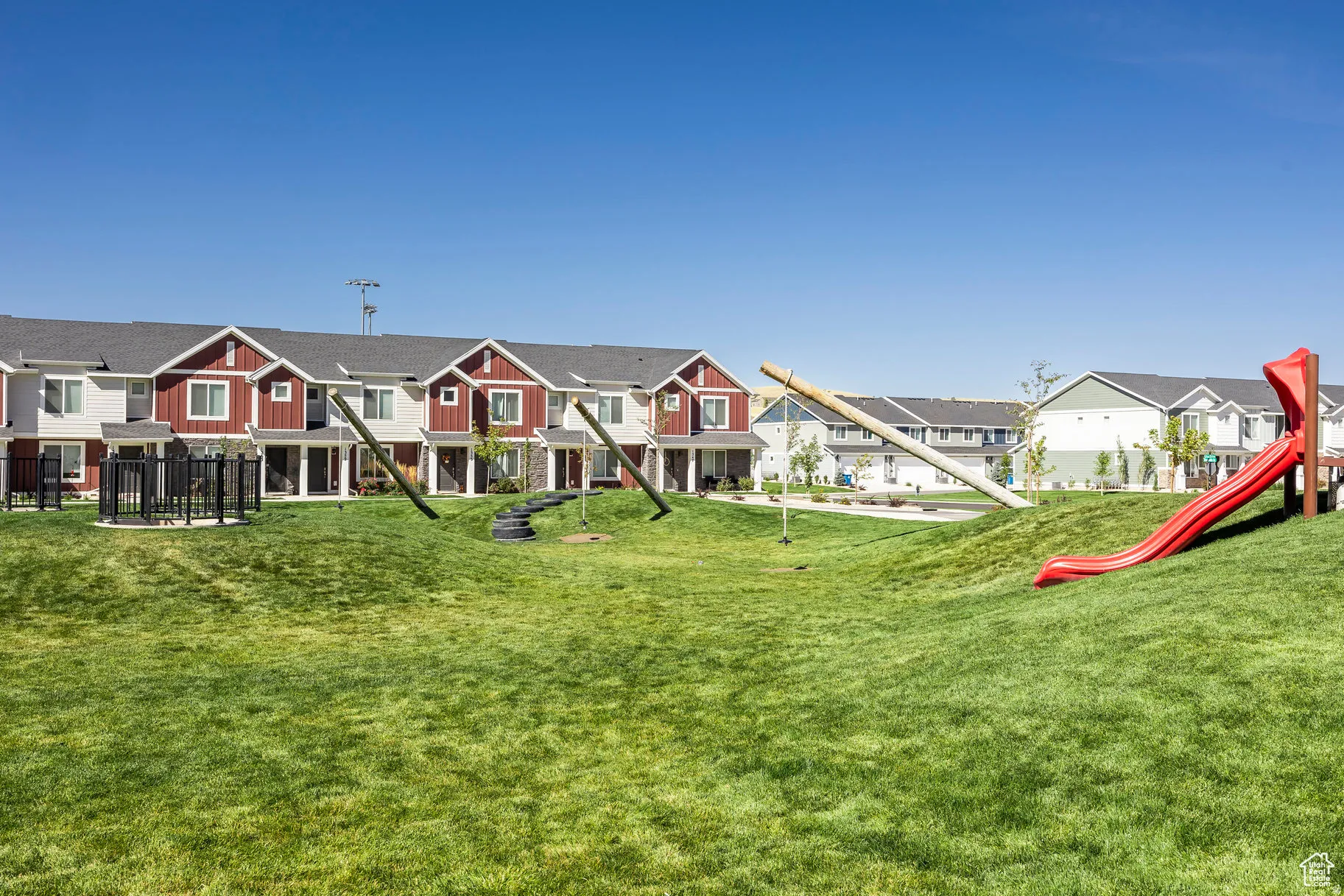 Expansive community green space with a red slide and tire swing