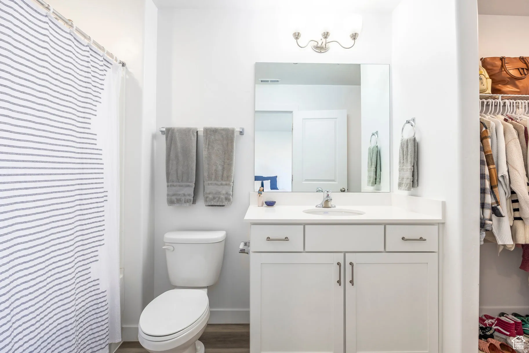 Bathroom featuring a white vanity with a single sink, light countertop, and brushed nickel hardware