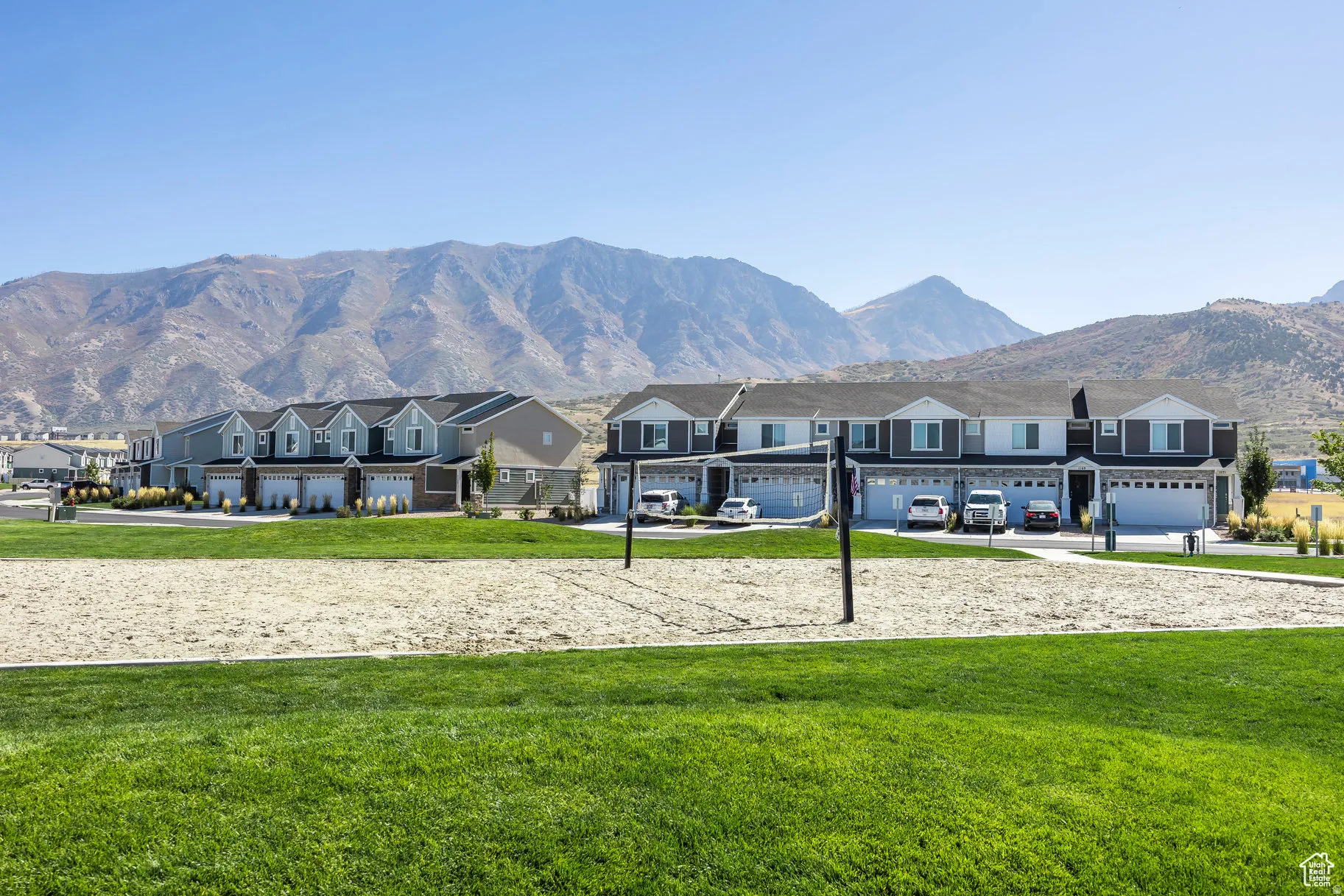 Expansive green space and sand court with distant mountain scenery