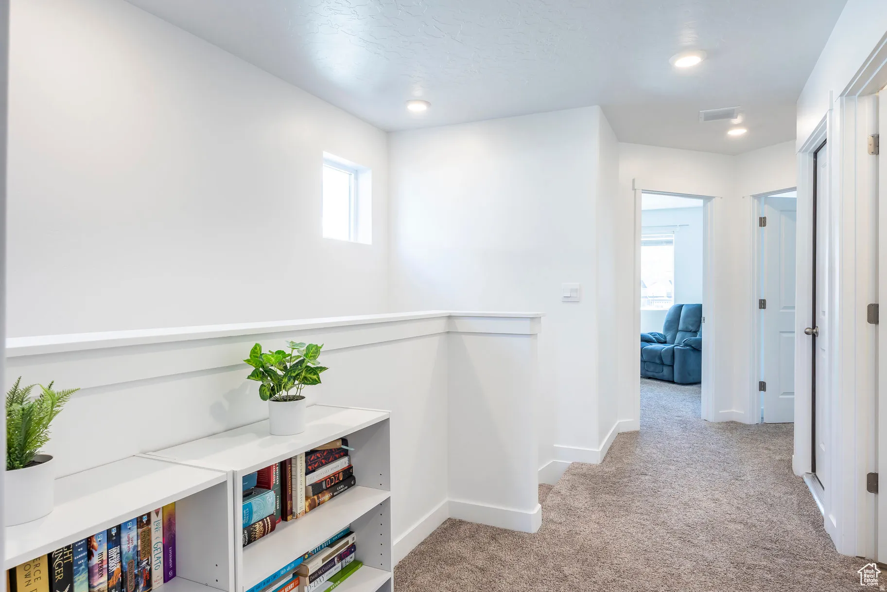 Upper-level landing featuring textured carpeting, white walls, and recessed lighting