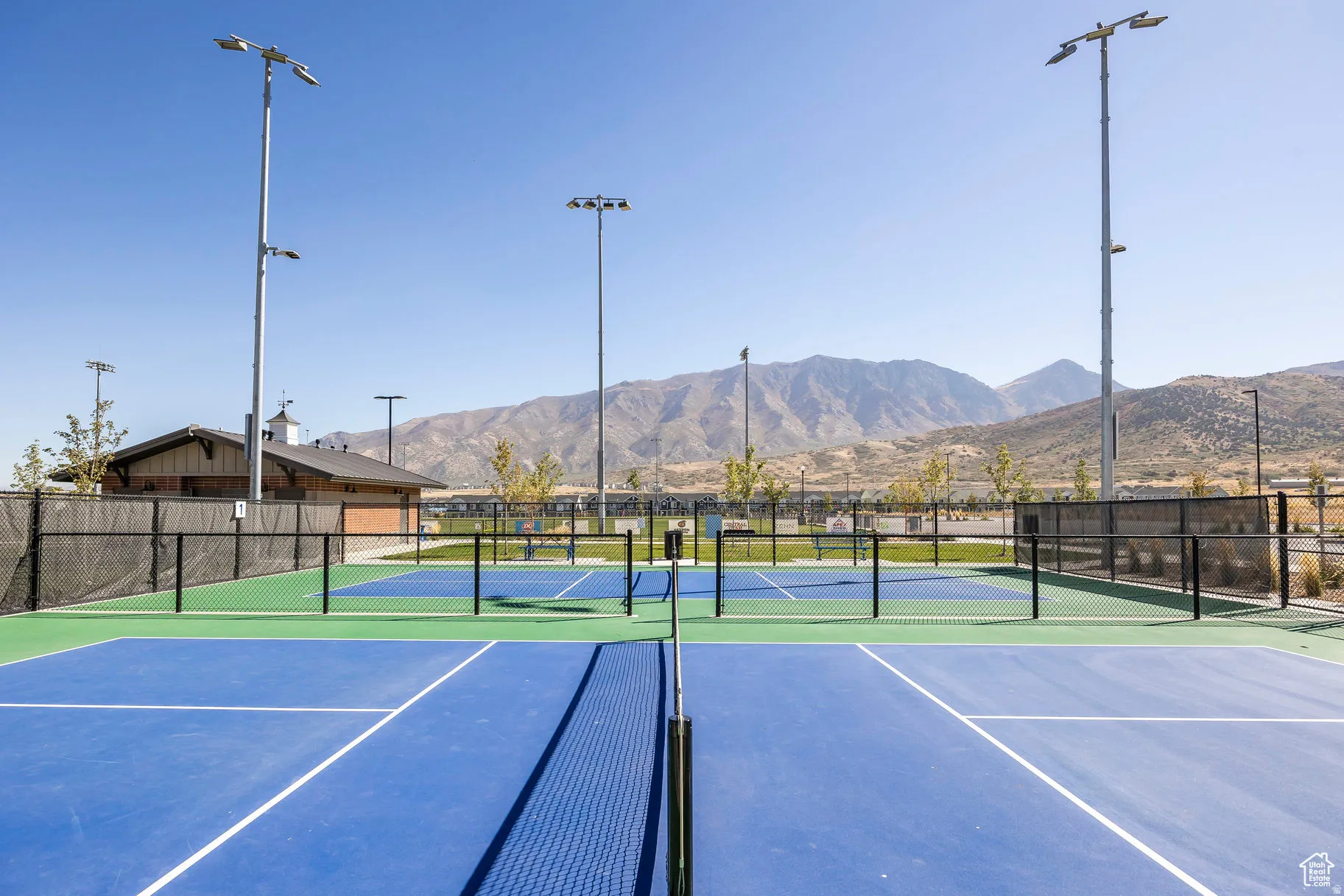 Pickleball courts featuring blue and green hard surfaces, surrounded by black chain-link fencing