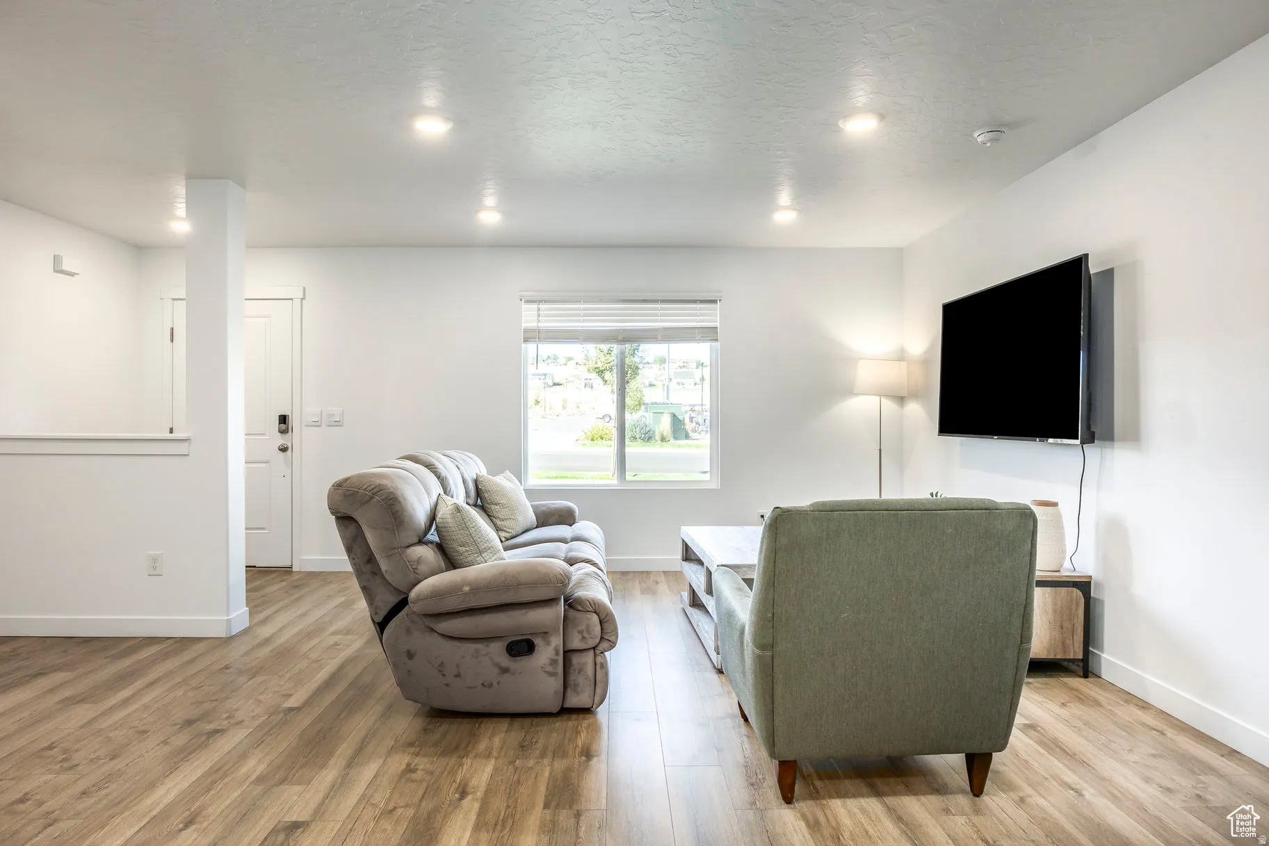 Bright living area featuring wood-finish flooring, recessed lighting, and a white trim window