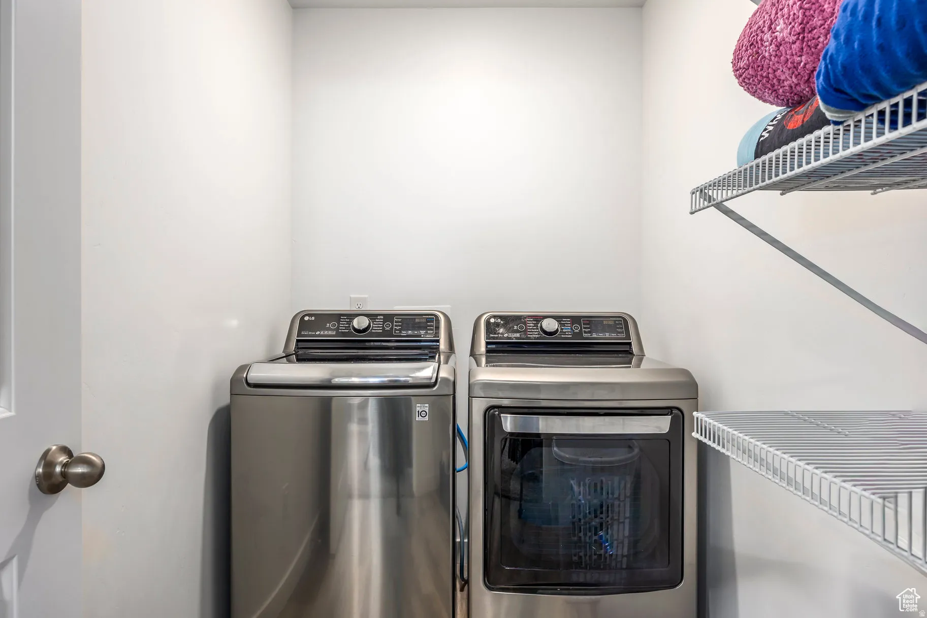 Dedicated laundry area featuring a white door with a brushed nickel knob, white walls, and a built-in wire shelving system