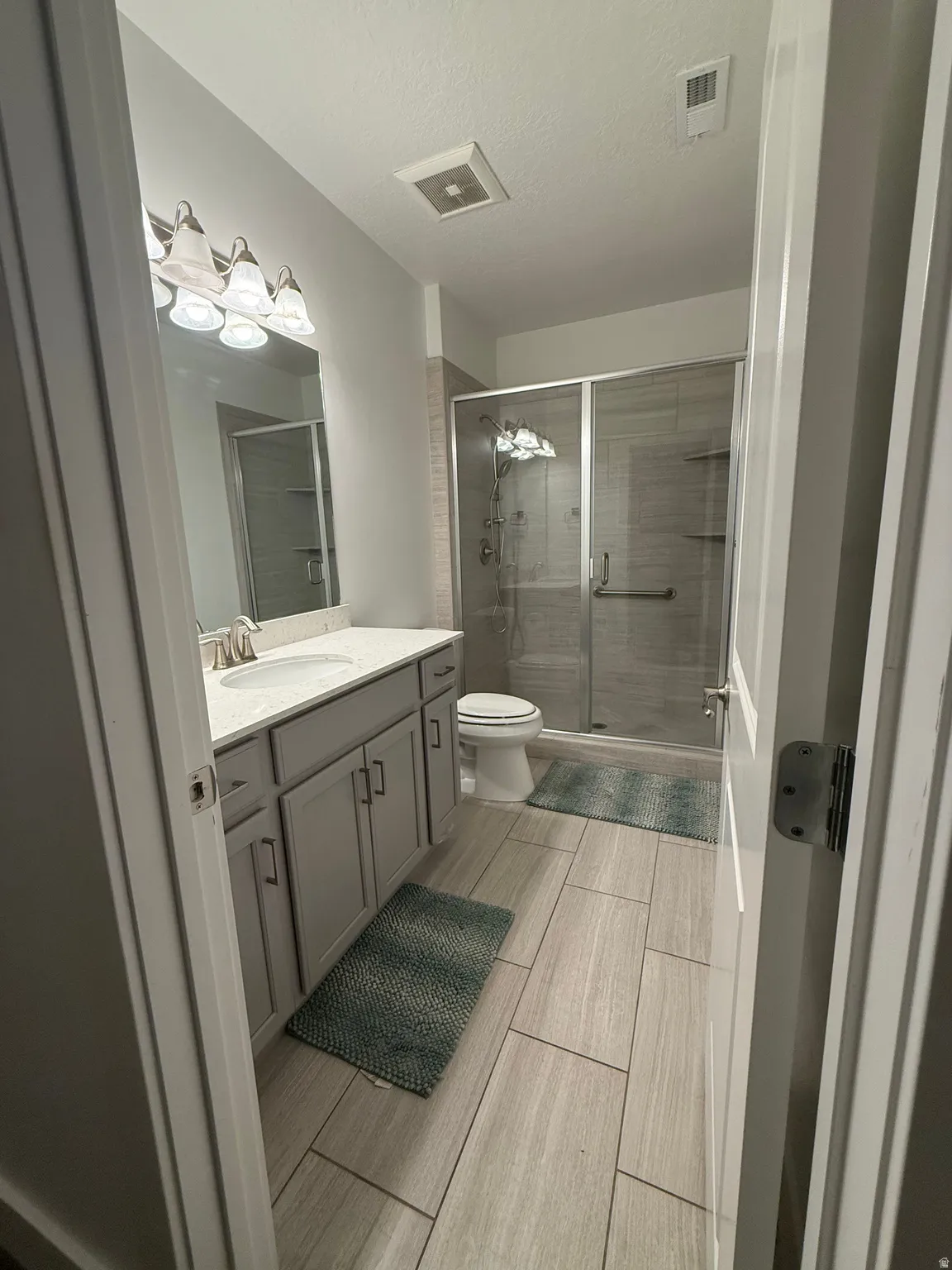 Bathroom featuring a single vanity with gray cabinetry, a white countertop, and a built-in sink