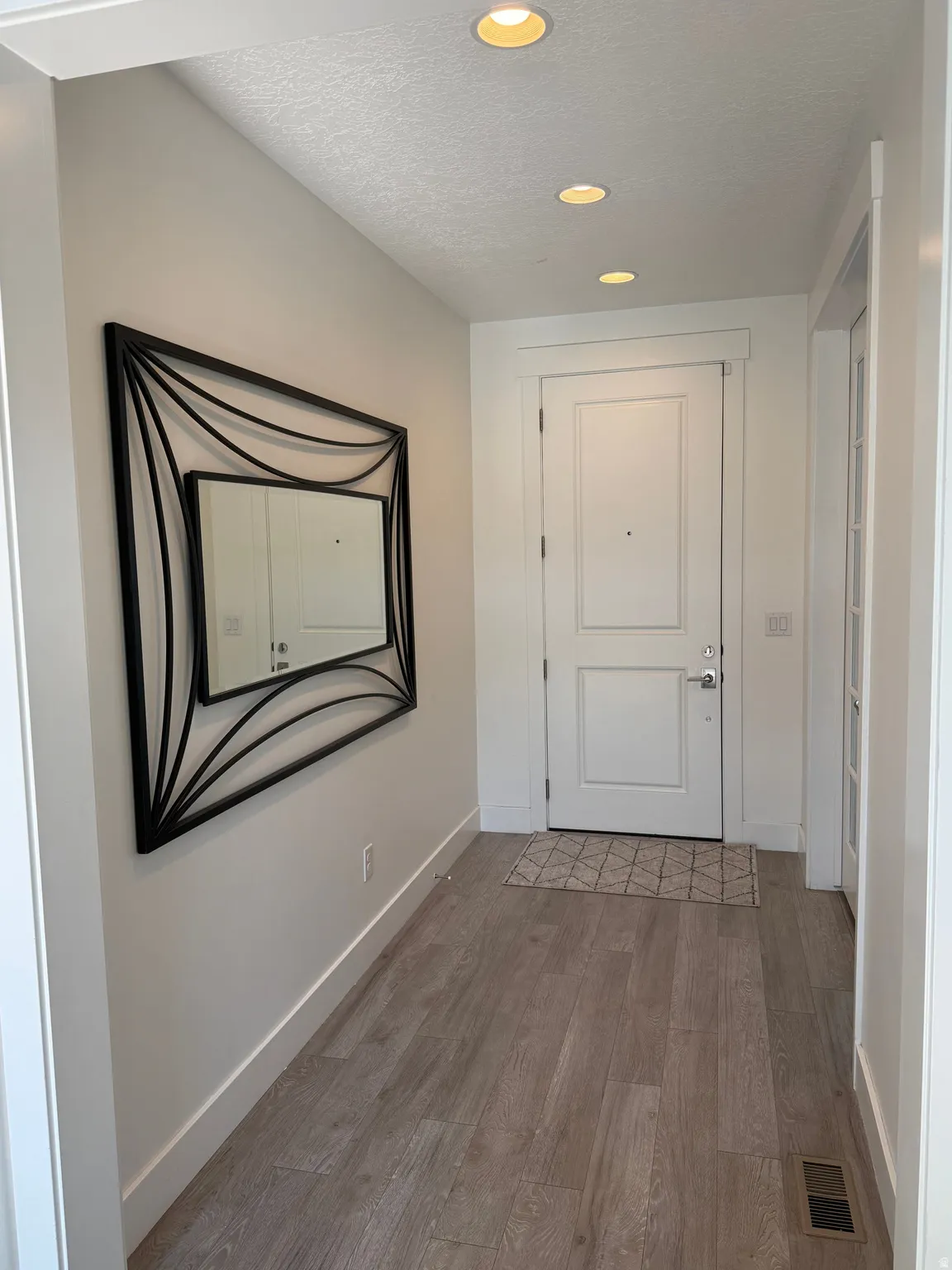 Entryway featuring wood-finish flooring, recessed lighting, and a white paneled door
