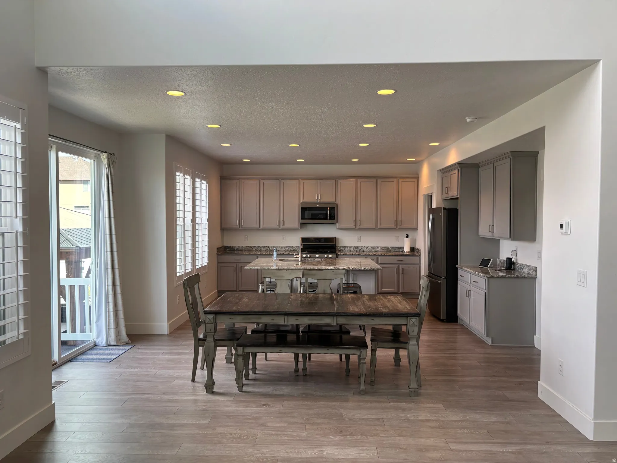 Recessed lighting, wood-finish flooring, kitchen island with seating, ample cabinetry, and stainless steel appliances