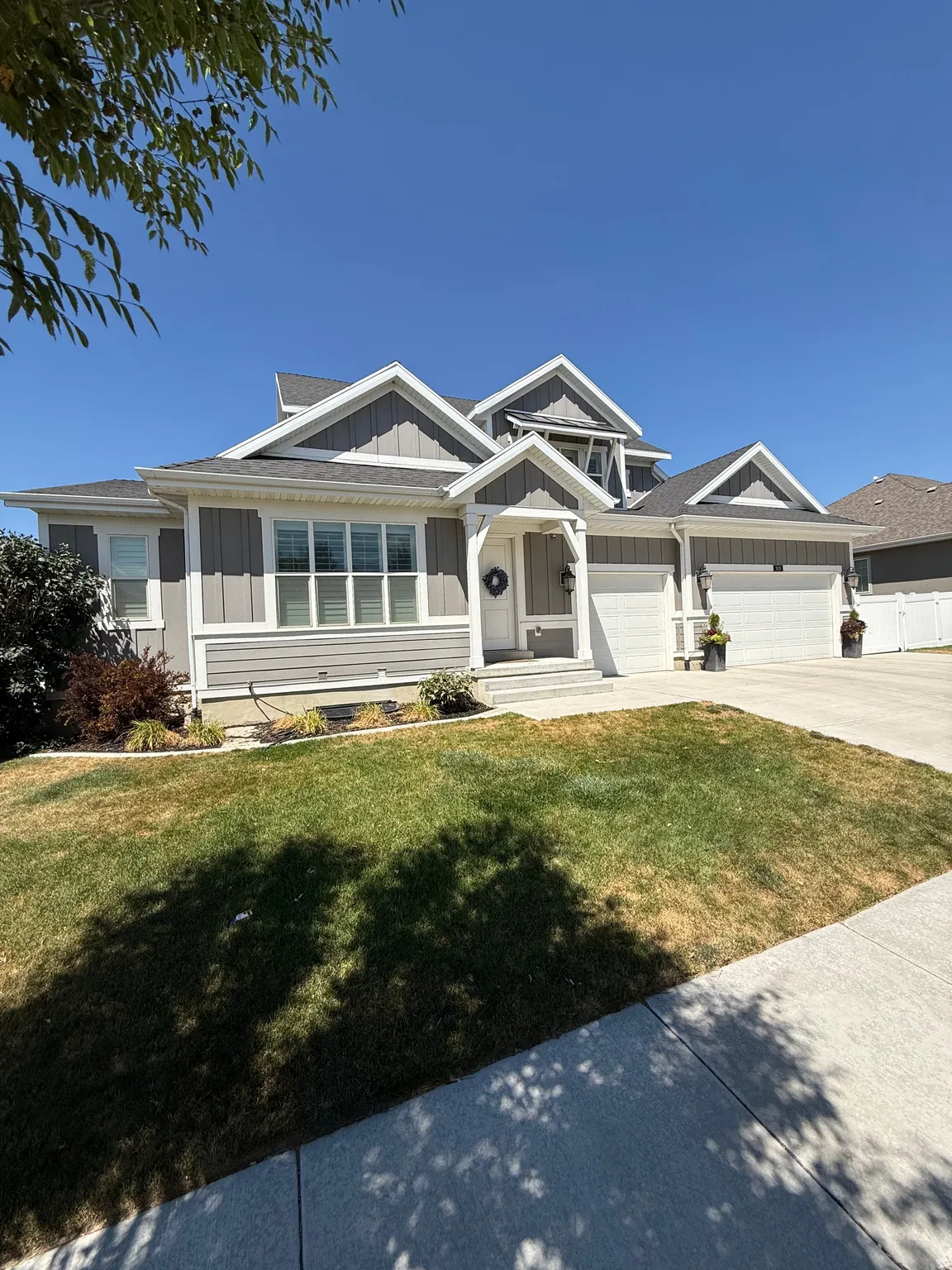 Gray siding with white trim, multiple gables, and a prominent front entrance with a covered porch