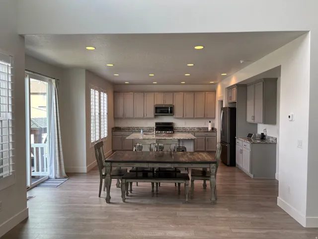 Recessed lighting, wood-finish flooring, kitchen island with seating, ample cabinetry, and stainless steel appliances