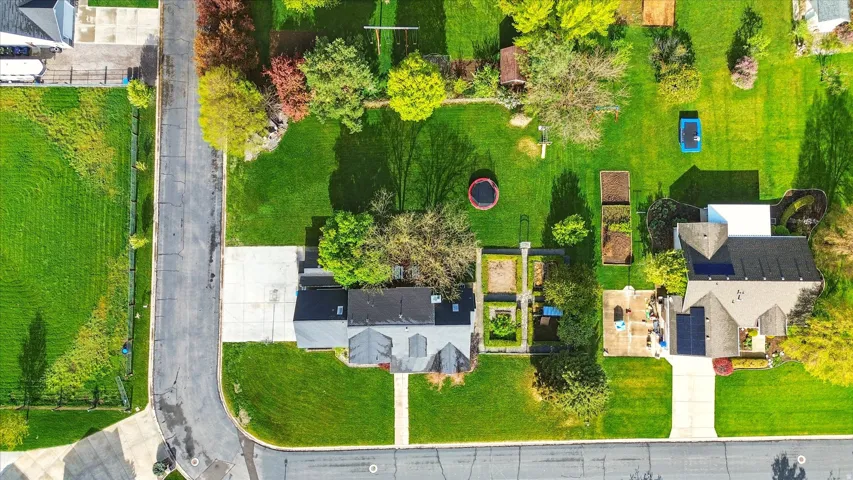 Expansive lot featuring a large lawn, mature trees, and established garden beds