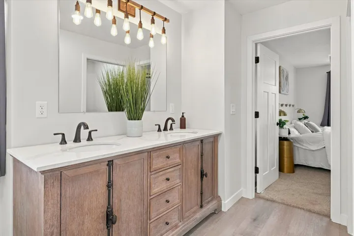 Double vanity featuring a light wood-finish cabinet, white countertop, and dual undermount sinks with matte black fixtures
