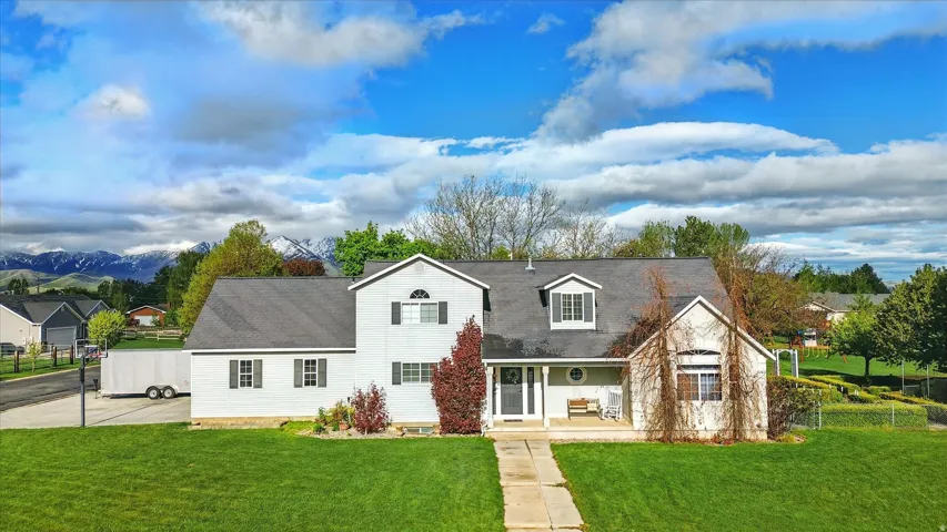 Charming two-story residence featuring a white exterior with brick accents, multiple gabled rooflines, and a covered entry portico