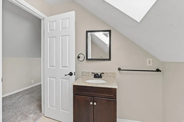 Elegant bathroom vanity featuring a dark wood cabinet base with dual doors, granite countertop, and single-basin sink paired with matte black hardware