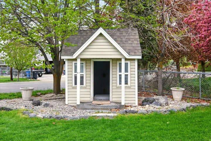 Detached outbuilding with light-colored siding and a gabled roof