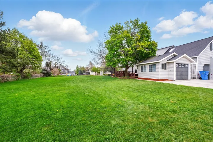 Expansive green lawn with a detached auxiliary structure featuring horizontal siding, multiple windows, and a single garage door