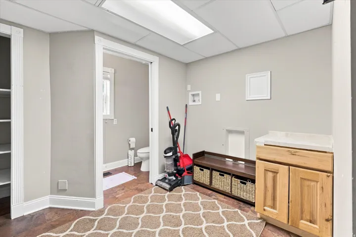 Utility room featuring built-in cabinetry, stone-finish countertop, and wood-finish flooring