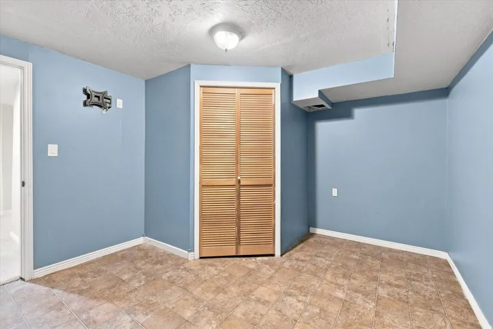 Room with blue walls, light brown square tile flooring, and a louvered bi-fold closet door