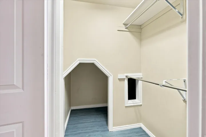 Closet space featuring shelving, hanging rods, and an additional storage alcove with blue flooring