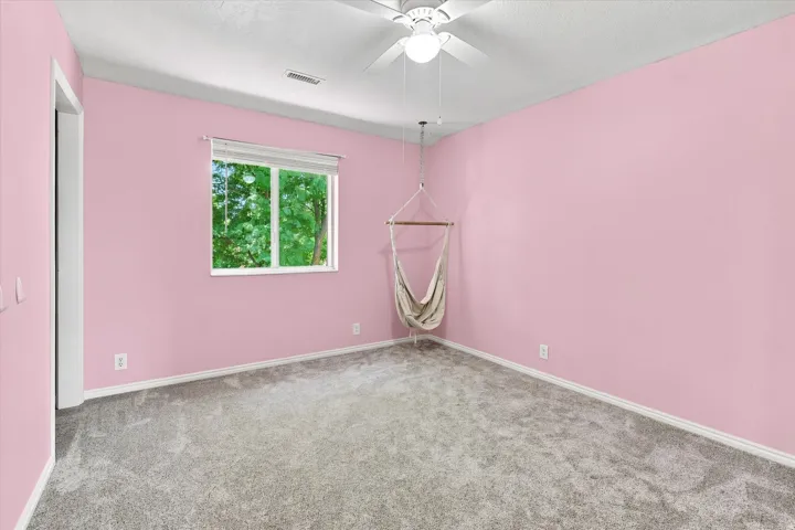 Spacious room featuring plush gray carpeting, light pink walls, and white trim