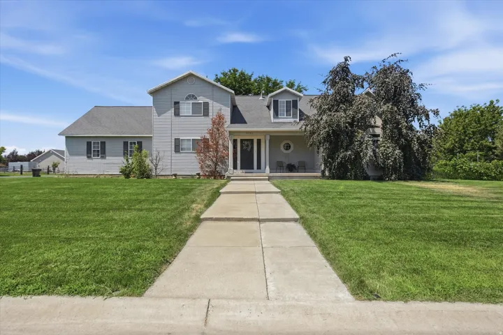 Two-story home with a light gray siding exterior, dark gray shingle roof, and a prominent front walkway