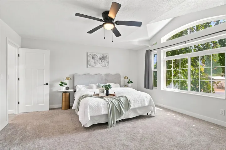 Spacious room featuring vaulted ceilings, a contemporary ceiling fan, and light-toned carpeting