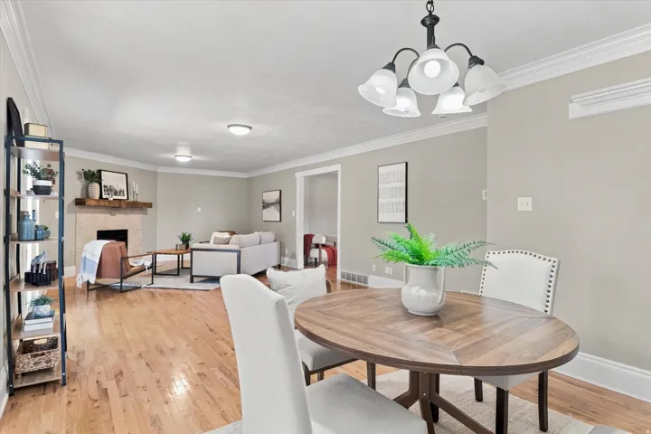 Open-concept living and dining area featuring warm wood-finish flooring, crown molding, and recessed lighting