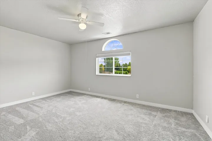 Spacious room featuring light gray carpet flooring, white baseboards, and neutral wall paint