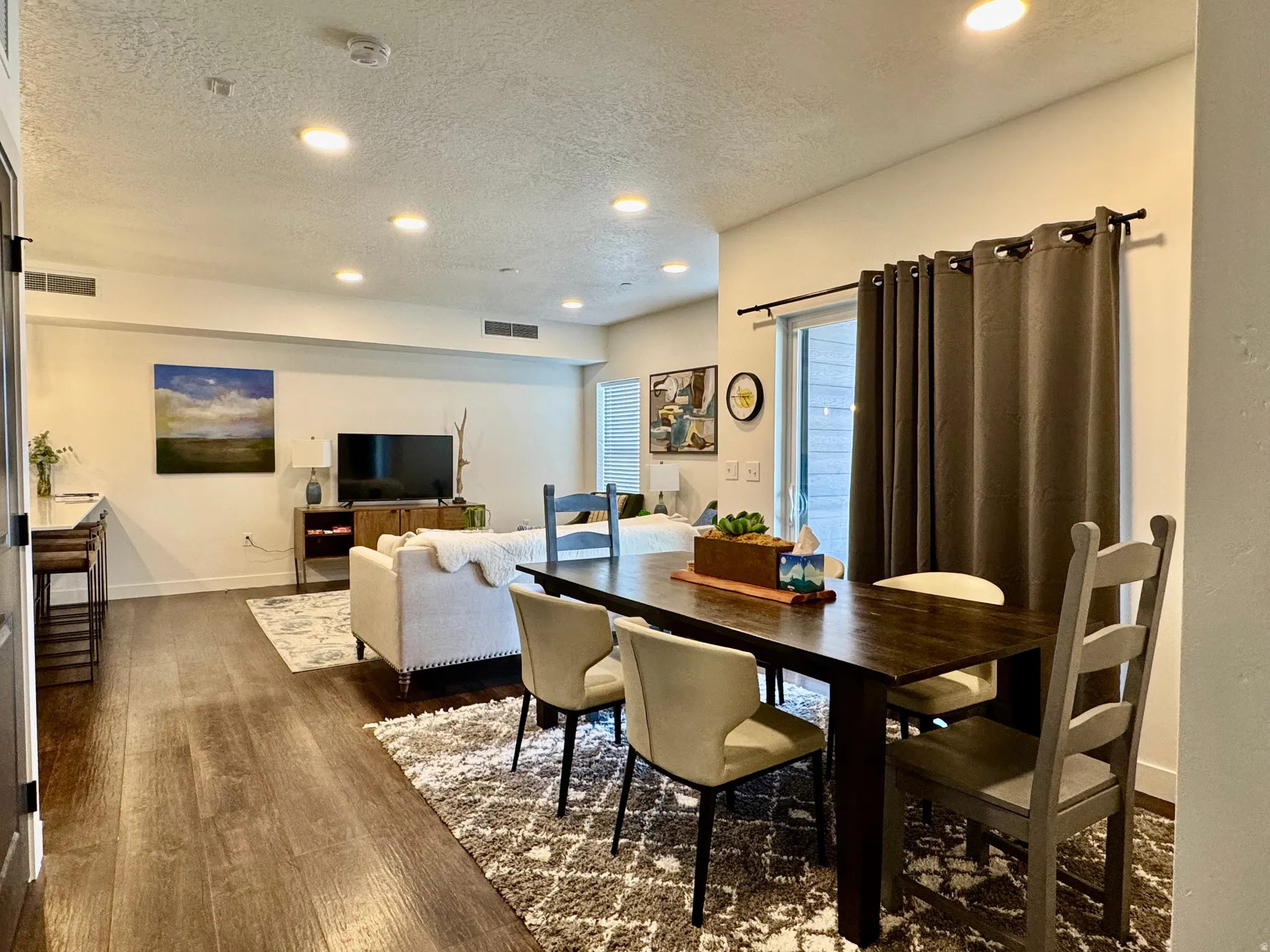 Open-concept living space featuring wood-finish flooring, recessed lighting, and a sliding glass door