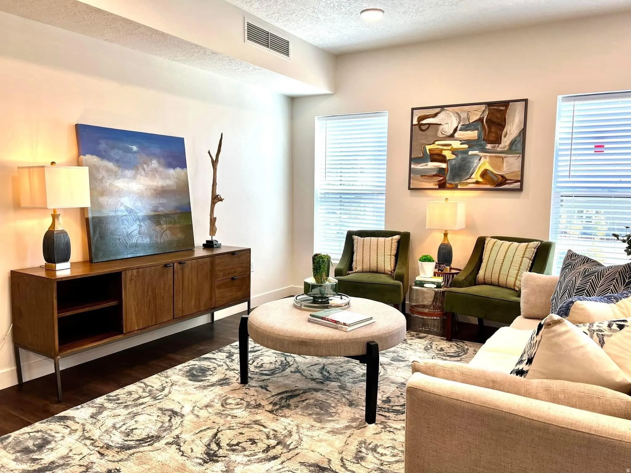 Spacious living area featuring dark wood-finish flooring, recessed lighting, and ample natural light from two windows