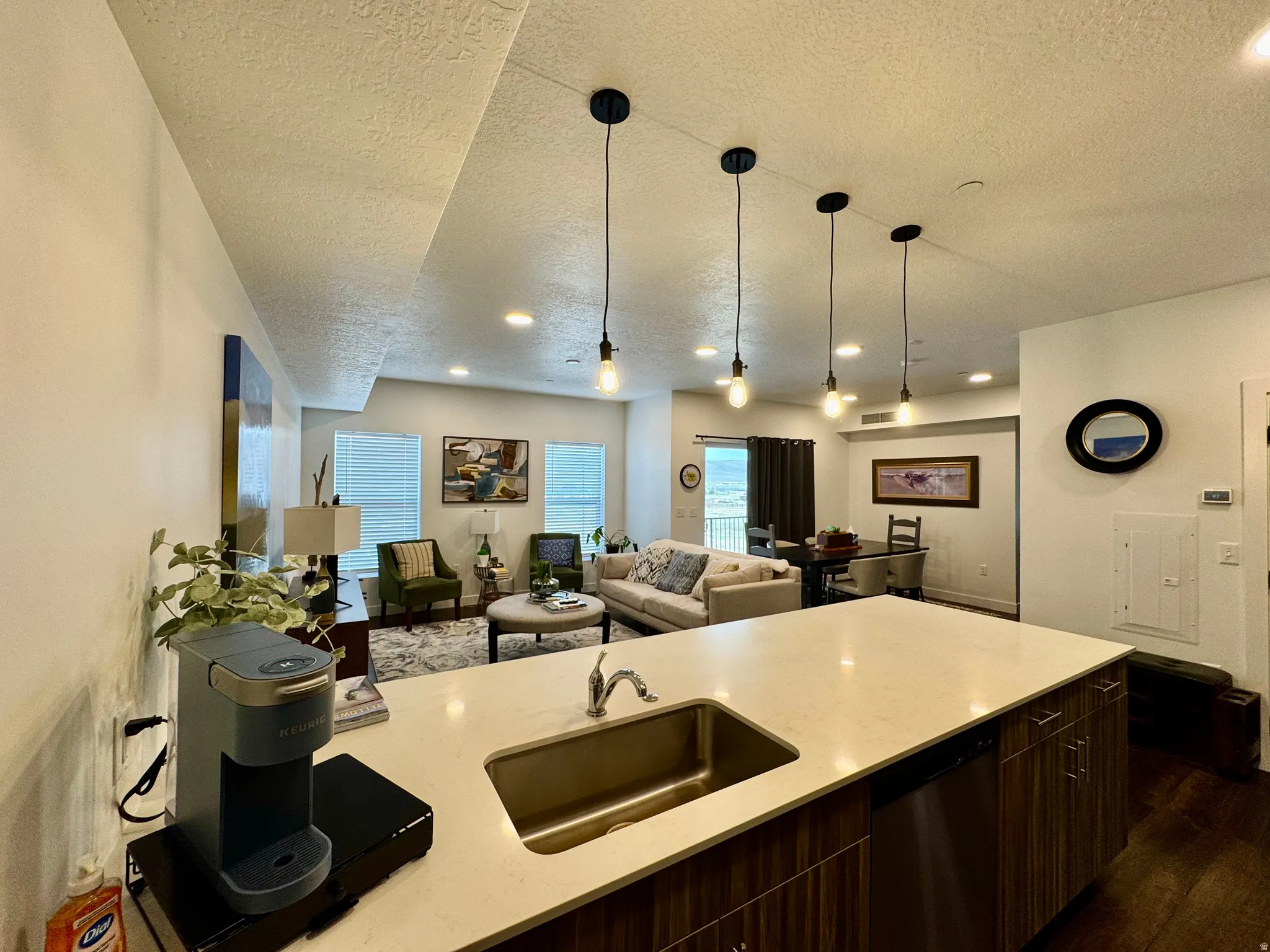 Kitchen island with a stainless steel undermount sink, a light-colored countertop, and integrated dishwasher