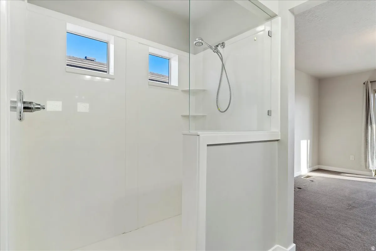 Walk-in shower featuring a glass enclosure, integrated shelving, and two transom windows