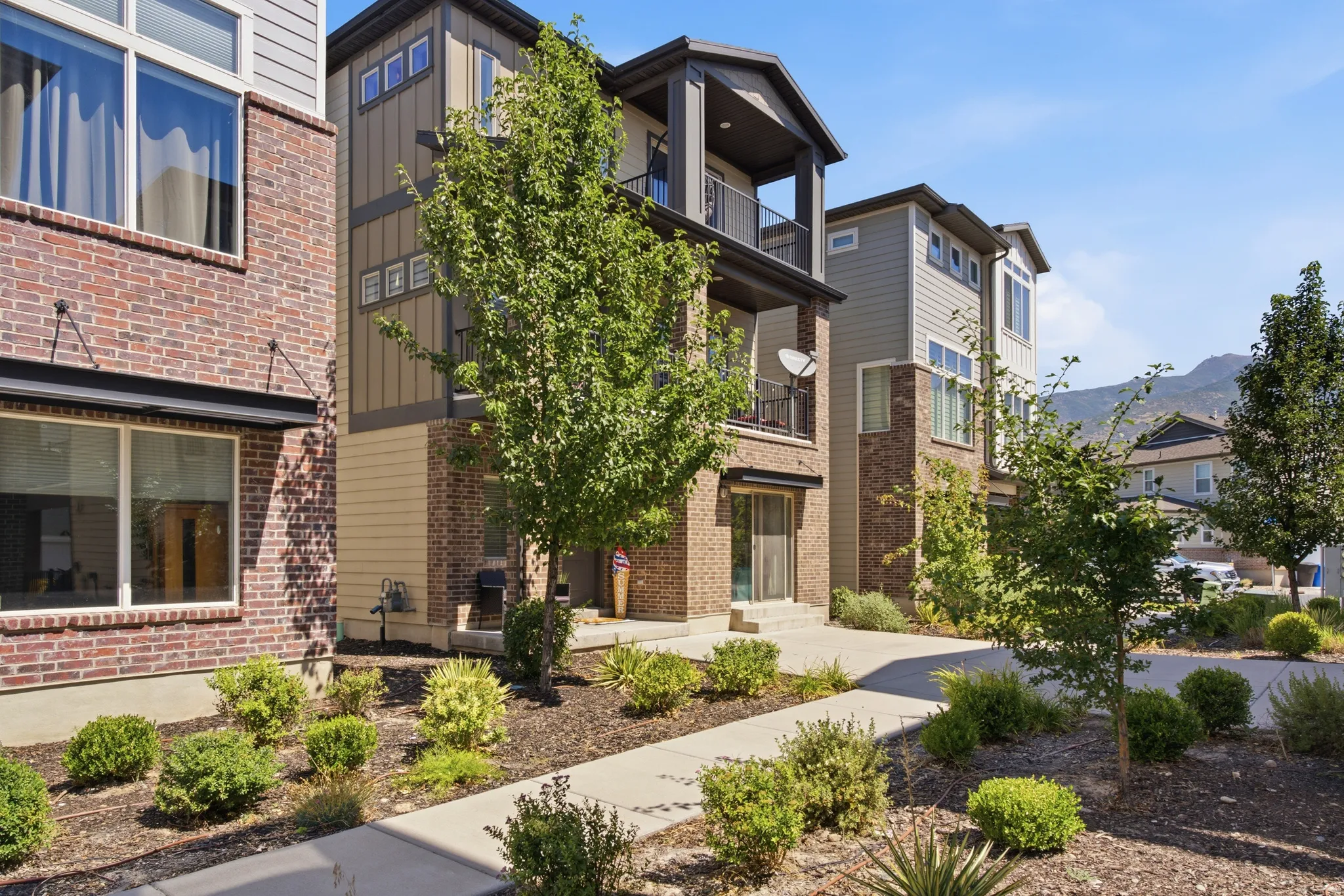 Modern exterior featuring multi-level architecture, brick and siding facade, large balconies, and landscaped front entryways with large porch and patio.