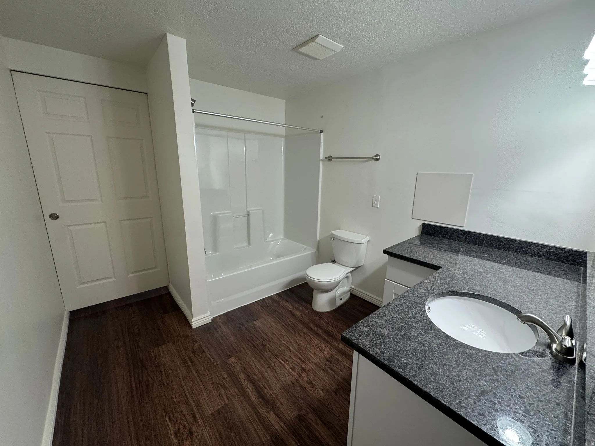 Bathroom featuring wood-finish flooring and a white vanity with a dark speckled countertop