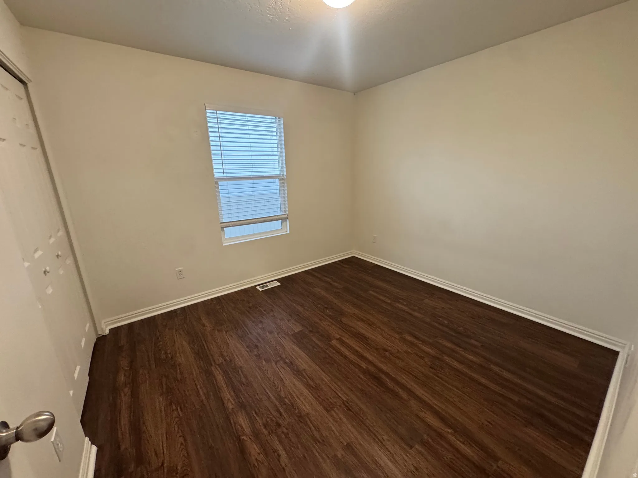 Room featuring wood-finish flooring, white baseboards, and neutral wall paint